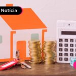 Miniatura de casa com moedas empilhadas ao lado.