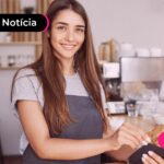 Jovem sorrindo segurando cartão de crédito