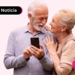 Idosos se abraçando enquanto usam celular para ler notícia sobre nova versão do aplicativo Meu INSS.