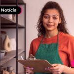 Trabalhadora CLT sorrindo enquanto lê notícia sobre possibilidade de escolher o consignado privado no Leilão na CTPS Digital.