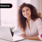 mulher com cabelo cacheado e blusa branca mexendo em um computador branco