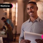 Assistente administrativo sorrindo após ler notícia sobre liberação do consigndo privado.