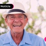 Pessoa de idade sorrindo após ler notícia sobre usar benefício do INSS para quitar dívidas.