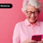 Pessoa de idade sorrindo enquanto usa celular para ler notícia sobre INSS.