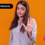 Jovem com expressão seria e mão fazendo simbolo de "pare".