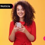 Pessoa sorrindo enquanto usa celular para ver portabilidade de consignado CLT.