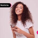 Jovem sorrindo enquanto usa celular para ler sobre escolha dos aplicativos para fazer consignado CLT.