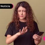 Pessoa com blusa preta segurando o celular.