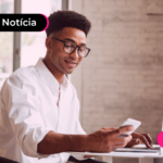 Pessoa de blusa branca com expressão feliz olhando para o celular.