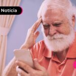 Pessoa idosa segurando o celular enquanto está com a outra mão na testa.
