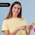 Pessoa com blusa amarela sorrindo enquanto segura o celular.
