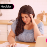 Pessoa jovem olhando para papéis enquanto apoia a mão esquerda na cabeça.