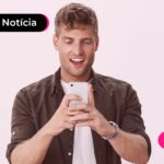 Jovem sorrindo segurando celular.