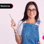 Pessoa de blusa branca e jardineira com o braço direito levemente levantado.