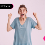 Pessoa de blusa azul com os dois braços para cima com expressão feliz.