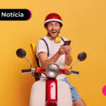 Pessoa sentada em cima de motocicleta segurando o celular com expressão feliz.