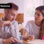 Pessoas de blusa branca lado a lado olhando para calculadora com expressão desanimda.