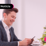 Pessoa de terno segurando celular com expressão feliz.