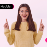 Pessoa de blusa amarela apontando os dois dedos para cima.