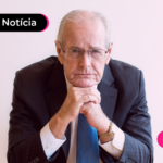 Pessoa idosa de terno com as duas mãos no queixo.