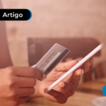 Pessoa segurando um cartão e um celular, aparentemente realizando uma compra online.
