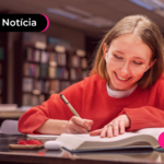 Pessoa de blusa vermelha em biblioteca com expressão feliz.