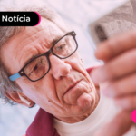 Idoso com espressão chateada mexendo no celular