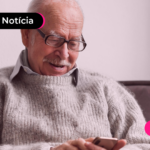 Pessoa idosa olhando celular com expressão feliz.