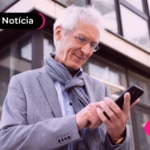 Pessoa idosa olhando celular com expressão feliz.