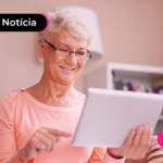 Pessoa idosa olhando para tablet com expressão feliz.