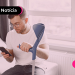Pessoa com muleta ortopédica olhando para celular.