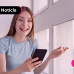Jovem sorrindo enquanto segura celular para ler notícia sobre Lucro do FGTS.