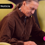 Pessoa idosa de blusa marrom olhando para computador.