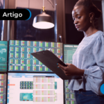 Mulher analisando gráficos e dados em várias telas, ambiente de análise financeira ou investimentos.