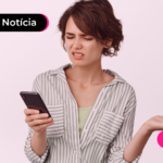 Pessoa de blusa listrada olhando o celular com expressão confusa.