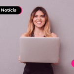 Pessoa de vestido preto olhando para computador com expressão feliz.