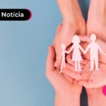 Mão segurando bonecos de papel simbolizando família.