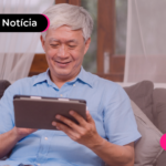 Pessoa idosa olhando para tablet com expressão feliz.