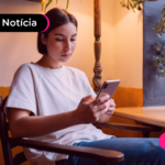 Pessoa de blusa branca olhando para aparelho celular.