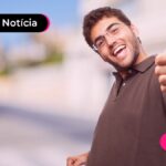 Jovem sorrindo enquanto faz sinal de joinha.