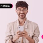 Pessoa sorrindo enquanto usa celular para ler notícia sobre Pix.