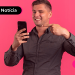 Pessoa de camisa social preta apontando para celular com expressão feliz.