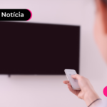 Pessoa com controle olhando para televisão.