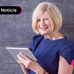 Pessoa idosa mexendo em tablet enquanto está sorrindo.