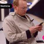 Pessoa em cadeira de rodas olhando para celular com expressão séria.