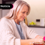 Pessoa idosa olhando para celular com expressão feliz.