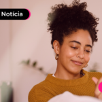 Jovem sorrindo enquanto usa celular para ler notícia sobre portabilidade para o consignado CLT.