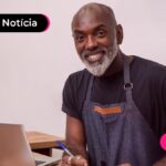 Homem contente ao ler notícia sobre pagamento de DAS por cartão de crédito disponível para MEIs.