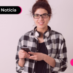 Pessoa de camisa xadrez segurando celular com expressão feliz.