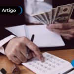 Pessoa de terno contando notas de dólar enquanto usa uma calculadora em mesa de escritório, representando cálculos financeiros e gestão de dinheiro.